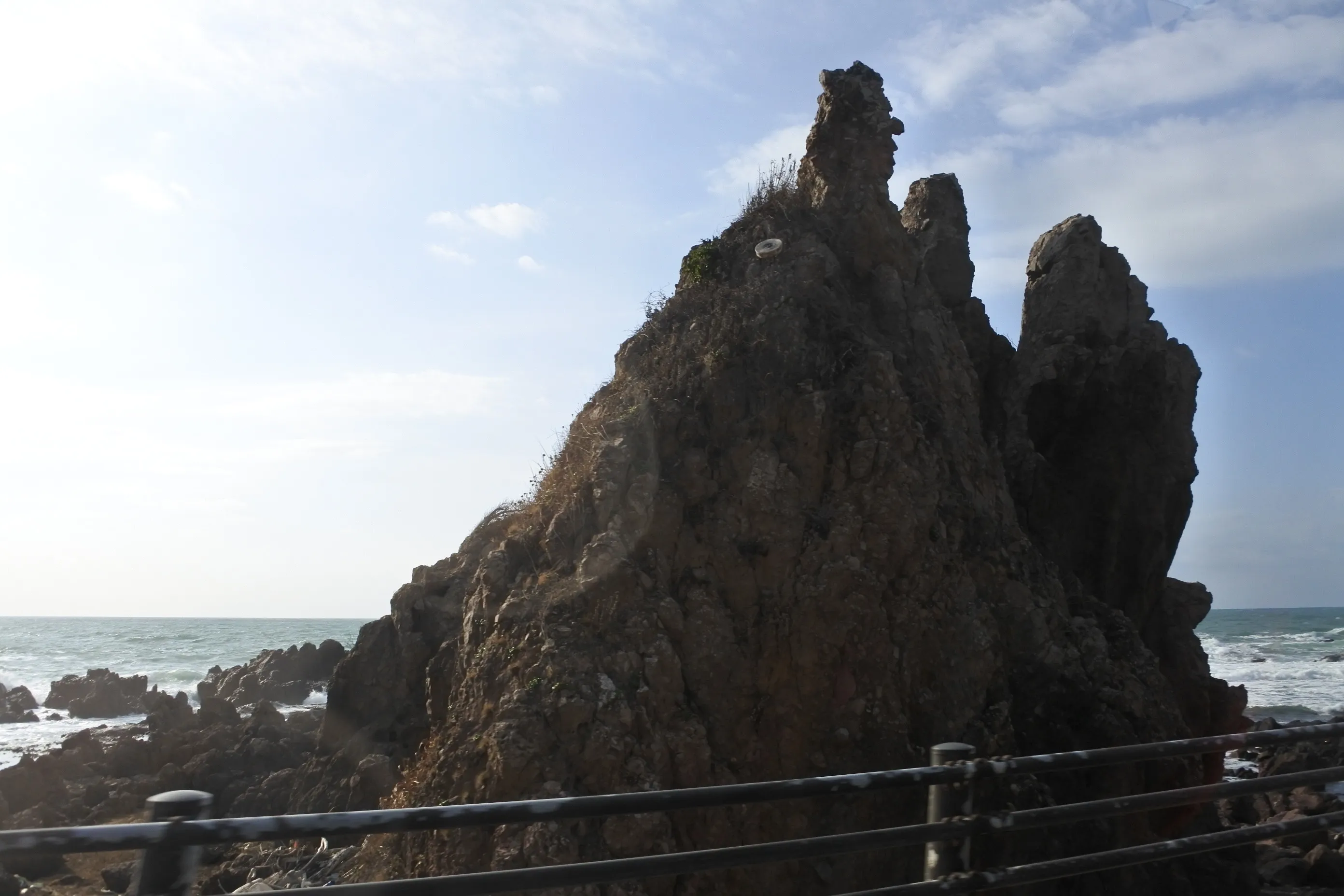 軍艦のように海にそびえる岩礁（通称：軍艦島）。白波がその輪郭を際立たせる