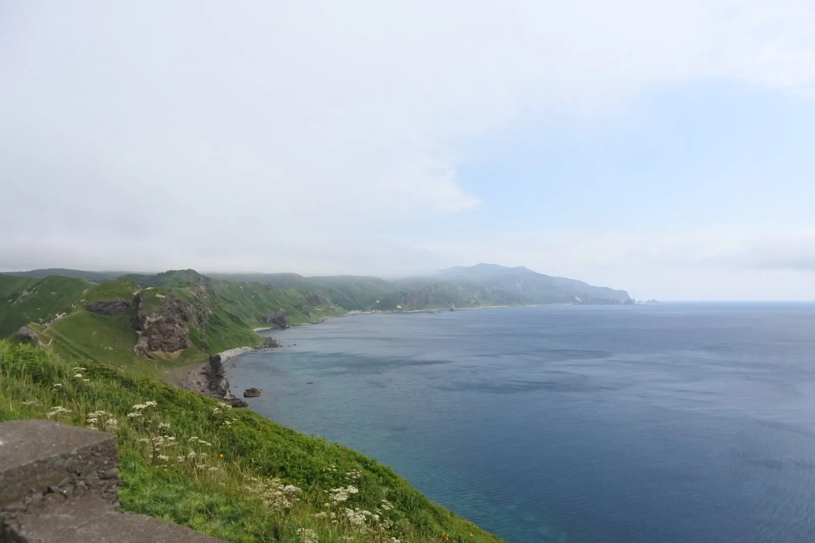 高台から見下ろす入り江。手前の浅瀬は明るい青緑、沖は濃紺で、青の濃淡がくっきり分かれている