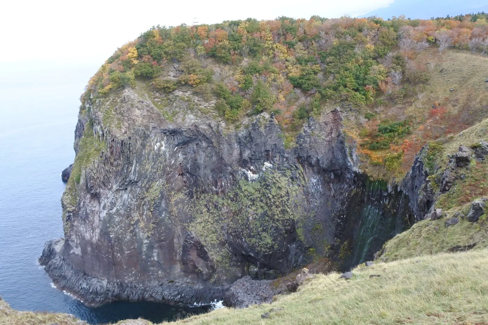 フレペの滝。草地の断崖の先端と、岩壁のくぼみを伝って幾筋もの水が海へ落ちている。左手は海