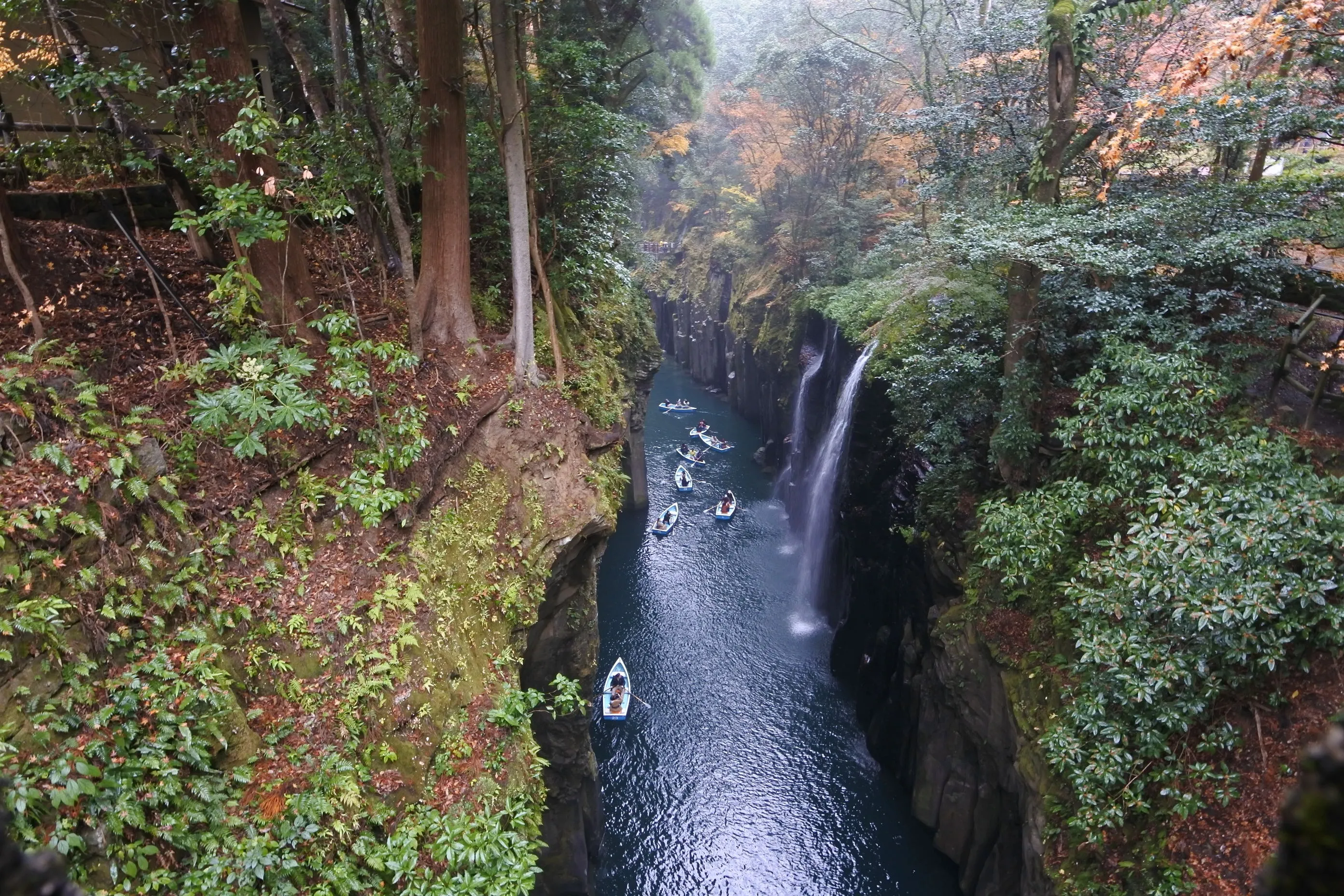 高千穂峡の全景。垂直に切り立つ柱状節理の崖の間に、真名井の滝と貸しボートが浮かぶ